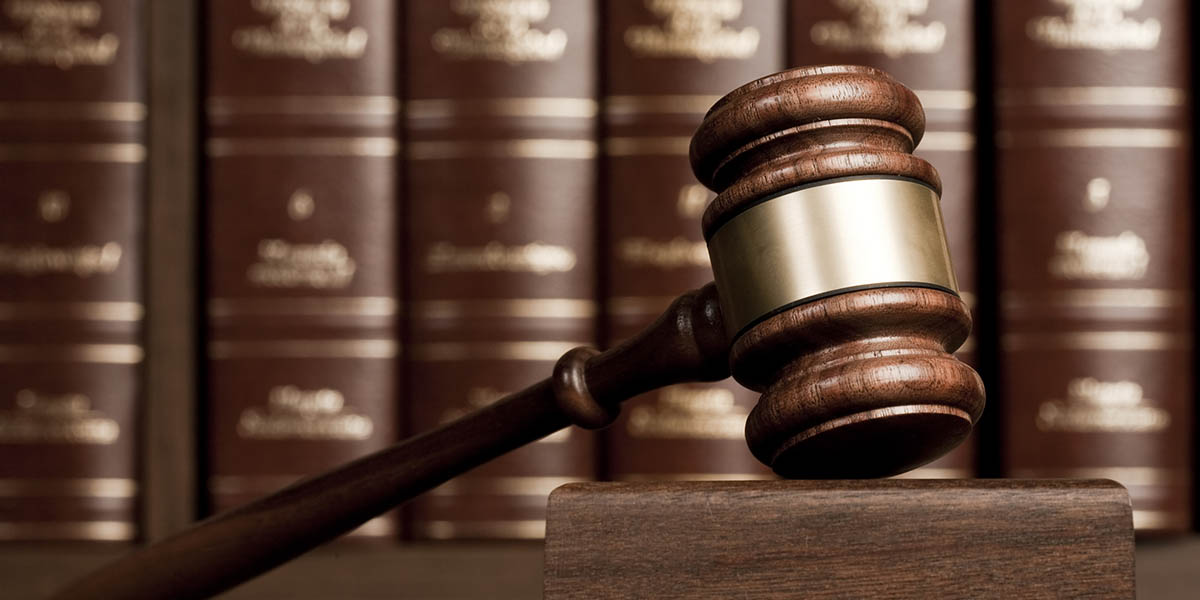 Gavel on wooden desk with books as background